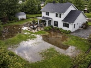 Aerial view of standing water surrounding a residential property after heavy rain, highlighting flood risks identified through an elevation survey.