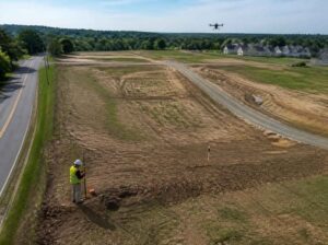 Surveyor and drone documenting a multi-parcel subdivision site with new roads and marked lots near Pembroke Pines, Florida.